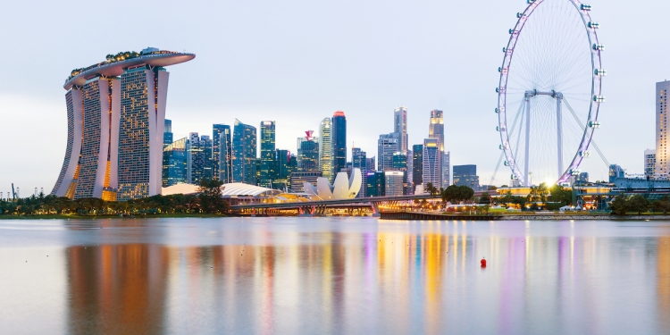 Singapore City Skyline with Marina Bay Sands hotel (left) and the Singapore Flyer ferris wheel, showing reflection in the still water at twilight