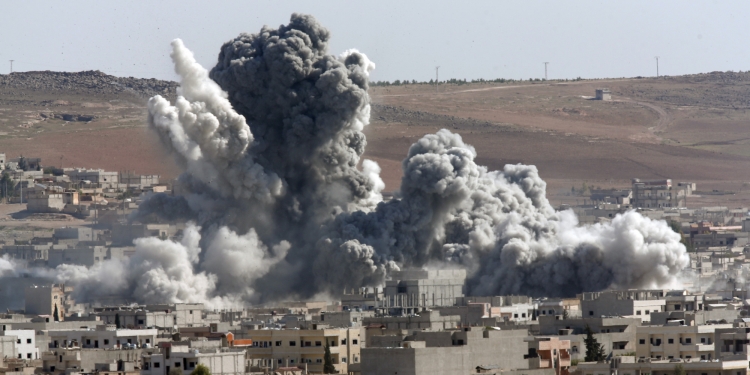 Thick smoke from an airstrike by the US-led coalition rises in Kobani, Syria, as seen from a hilltop on the outskirts of Suruc, at the Turkey-Syria border, Wednesday, Oct. 22, 2014. Kobani, also known as Ayn Arab, and its surrounding areas, has been under assault by extremists of the Islamic State group since mid-September and is being defended by Kurdish fighters. (AP Photo/Lefteris Pitarakis)