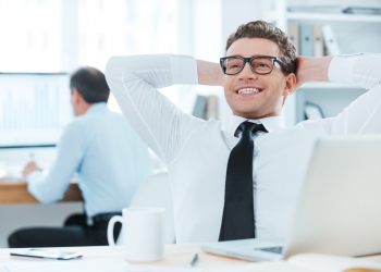 Satisfied with the work done. Cheerful businessman in formalwear holding head in hands while sitting at his desk in the office