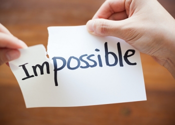 Hands Tearing Paper with the Words - Impossible become Possible