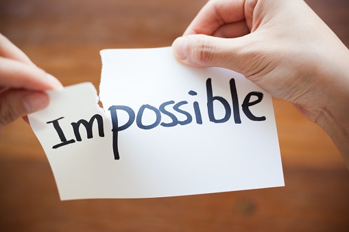 Hands Tearing Paper with the Words - Impossible become Possible