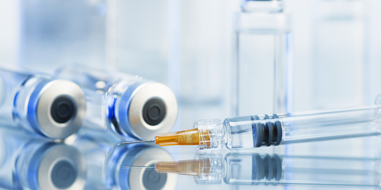 Syringe. Disposable plastic medical syringe surrounded by sealed medication vials.