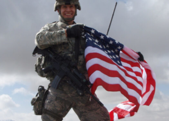 Maj. Joseph Zackaricz unfurls an American flag while atop an Afghanistan mountain while on a patrol for Taliban insurgents. (U.S. Air Force photo/Capt. Chad Sitzman)