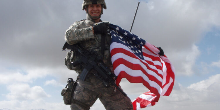 Maj. Joseph Zackaricz unfurls an American flag while atop an Afghanistan mountain while on a patrol for Taliban insurgents. (U.S. Air Force photo/Capt. Chad Sitzman)