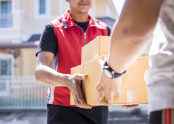 parcel delivery man of a package through a service and customer hand accepting a delivery of boxes from delivery man.