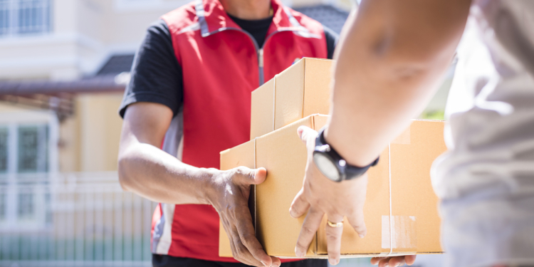 parcel delivery man of a package through a service and customer hand accepting a delivery of boxes from delivery man.