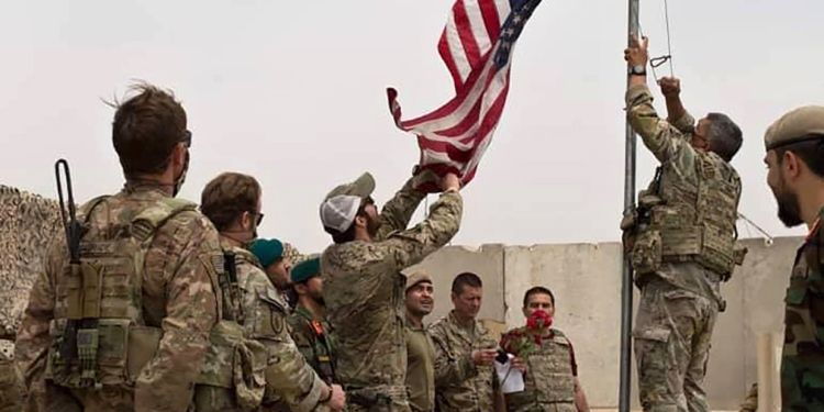 A U.S. flag is lowered as American and Afghan soldiers attend a handover ceremony from the U.S. Army to the Afghan National Army, at Camp Anthonic, in Helmand province, southern Afghanistan, Sunday, May 2, 2021. (Afghan Ministry of Defense Press Office via AP)