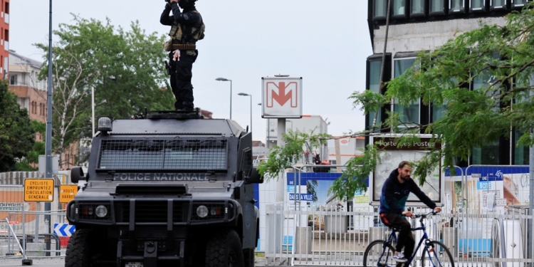 A French Recherche Assistance Intervention Dissuasion (RAID) special police unit member stands on his armoured car and uses his binoculars to check a protest following the death of Nahel, a 17-year-old teenager killed by a French police officer in Nanterre during a traffic stop, in Lille, France, 30 June 2023. REUTERS/Pascal Rossignol