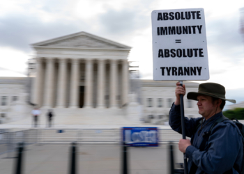 A demonstrator holds a sign outside the US Supreme Court in Washington, DC, US, on Thursday, April 25, 2024. The justices are expected to hear arguments today in a historic showdown likely to determine whether former US President Donald Trump stands trial in federal court in Washington for allegedly inciting the Jan. 6 Capitol riot and trying to overturn the 2020 election. Photographer: Nathan Howard/Bloomberg