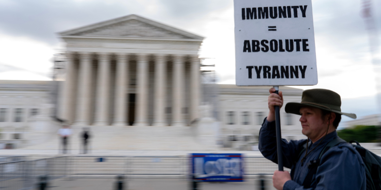 A demonstrator holds a sign outside the US Supreme Court in Washington, DC, US, on Thursday, April 25, 2024. The justices are expected to hear arguments today in a historic showdown likely to determine whether former US President Donald Trump stands trial in federal court in Washington for allegedly inciting the Jan. 6 Capitol riot and trying to overturn the 2020 election. Photographer: Nathan Howard/Bloomberg