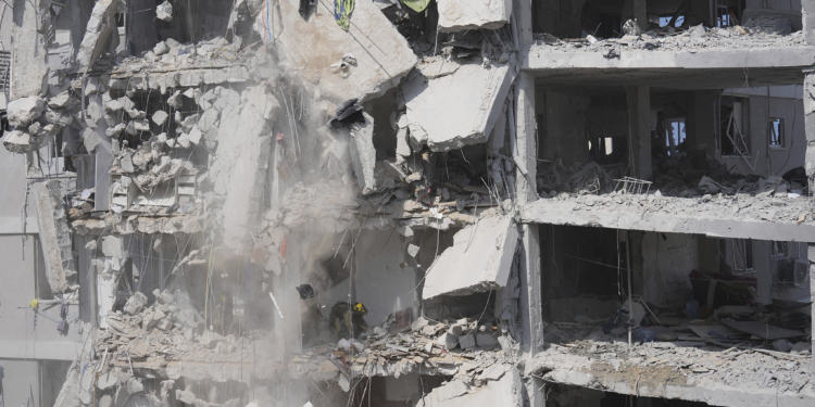 Concrete and rubble fall from a heavily damaged building as Israeli soldiers search for survivors in a residential area hit by a missile fired from Iran, near Tel Aviv, Israel, Sunday, June 15, 2025.(AP Photo/Ariel Schalit)