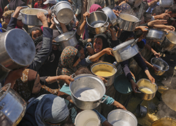 Palestinians struggle to get donated food at a community kitchen in Gaza City, northern Gaza Strip, Monday, Aug. 4, 2025. (AP Photo/Jehad Alshrafi)