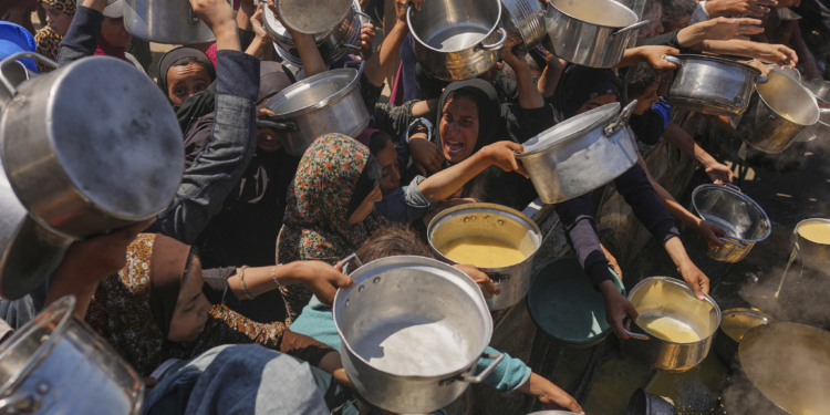 Palestinians struggle to get donated food at a community kitchen in Gaza City, northern Gaza Strip, Monday, Aug. 4, 2025. (AP Photo/Jehad Alshrafi)