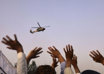 People wave to a military helicopter after it dropped flowers over the city during celebrations marking the fourth anniversary of the U.S. withdrawal and the start of Taliban rule in Kabul, Afghanistan, Friday, Aug. 15, 2025. (AP Photo/Siddiqullah Alizai)