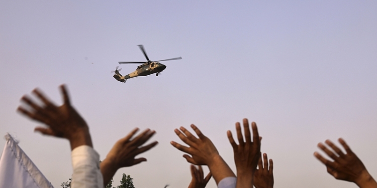 People wave to a military helicopter after it dropped flowers over the city during celebrations marking the fourth anniversary of the U.S. withdrawal and the start of Taliban rule in Kabul, Afghanistan, Friday, Aug. 15, 2025. (AP Photo/Siddiqullah Alizai)
