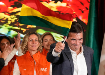 FILE - Presidential candidate Rodrigo Paz waves a Bolivian flag after preliminary results showed him leading in the presidential runoff election in La Paz, Bolivia, Oct. 19, 2025. (AP Photo/Natacha Pisarenko, File)