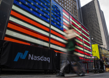 NEW YORK, NEW YORK - APRIL 03: A person walk near a Nasdaq’s banner in Times Square on April 03, 2025 in New York City.  U.S. president Donald Trump’s “liberation day” which refers to the tariff war, has affected some US-based global brands such as Nike or Apple which have suffered some of the heaviest falls in the market value. (Photo by Zamek/VIEWpress)