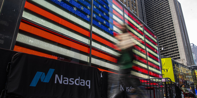 NEW YORK, NEW YORK - APRIL 03: A person walk near a Nasdaq’s banner in Times Square on April 03, 2025 in New York City.  U.S. president Donald Trump’s “liberation day” which refers to the tariff war, has affected some US-based global brands such as Nike or Apple which have suffered some of the heaviest falls in the market value. (Photo by Zamek/VIEWpress)