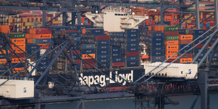 SHENZHEN, CHINA - APRIL 15: A Hapag-Lloyd container vessel is seen docked among gantry cranes and stacked shipping containers at Yantian International Container Terminals on April 15, 2026 in Shenzhen, Guangdong province, China. Hapag-Lloyd is one of the world’s major container shipping companies, and operations at Chinese ports such as Yantian highlight the scale of global trade and maritime logistics networks. (Photo by Cheng Xin/Getty Images)