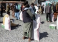 An Afghan man with his son wait to receive a food package distributed by a Saudi Arabia humanitarian aid group at a distribution center in Kabul, Afghanistan, April 25, 2022. REUTERS/Ali Khara/File Photo