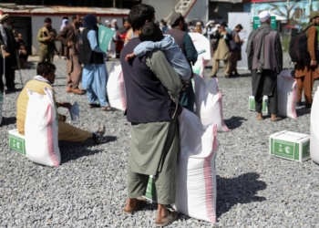An Afghan man with his son wait to receive a food package distributed by a Saudi Arabia humanitarian aid group at a distribution center in Kabul, Afghanistan, April 25, 2022. REUTERS/Ali Khara/File Photo