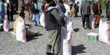 An Afghan man with his son wait to receive a food package distributed by a Saudi Arabia humanitarian aid group at a distribution center in Kabul, Afghanistan, April 25, 2022. REUTERS/Ali Khara/File Photo