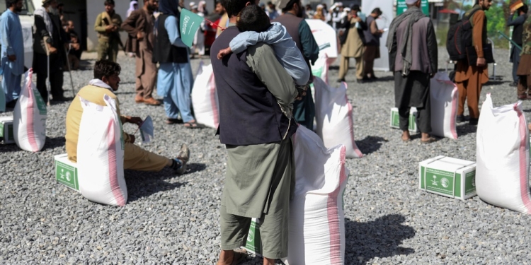 An Afghan man with his son wait to receive a food package distributed by a Saudi Arabia humanitarian aid group at a distribution center in Kabul, Afghanistan, April 25, 2022. REUTERS/Ali Khara/File Photo