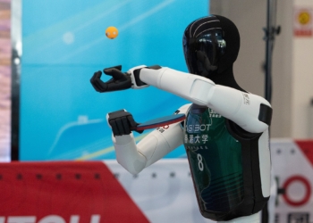A humanoid robot serves as it plays table tennis with a human during a media preview, ahead of the World Humanoid Robotic Games in Beijing, China, Friday, Aug. 14, 2026. (Andres Martinez Casares/Pool Photo via AP)