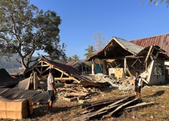 People stand near earthquake-damaged buildings in Satar Punda, East Nusa Tenggara province, Indonesia, Tuesday, Aug. 18, 2026. (AP Photo/Firdia Lisnawati)