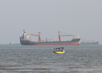 A boat floats as commercial vessels appear anchored in the Strait of Hormuz off Bandar Abbas, Iran, Tuesday, Oct. 13, 2026. (Razieh Poudat/ISNA via AP)